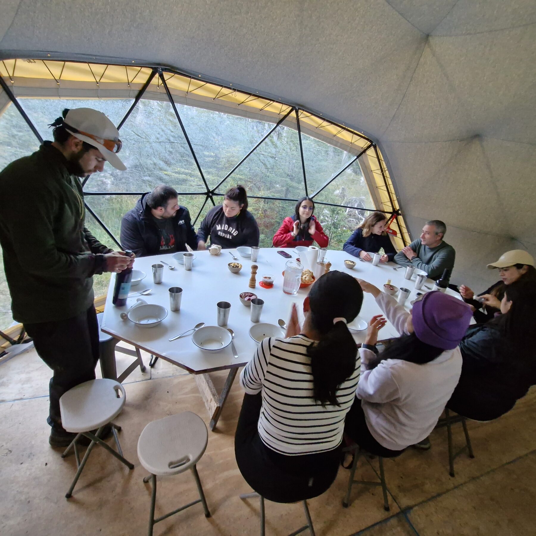 Interior del Domo Titan: un grupo compartiendo la mesa con el bosque al otro lado del ventanal