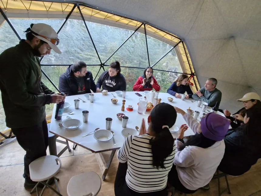 Interior del Domo Titan: un grupo compartiendo la mesa con el bosque al otro lado del ventanal